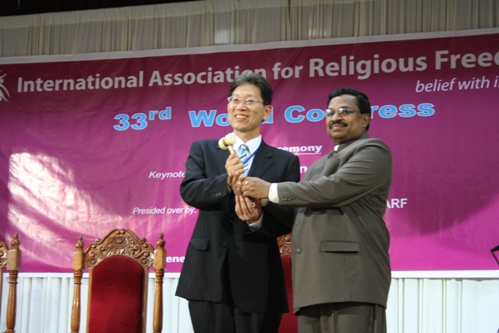 At right, outgoing president Dr. Thomas Mathew transferring the 'Dana Greeley' ivory gavel of office to his successor, Most Rev. Mitsuo Miyake of the Konko Church of Izuo, Osaka. 